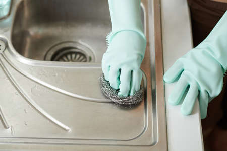 Close-up image of woman using metal sponge when cleaning aluminium kitchen sinkの写真素材