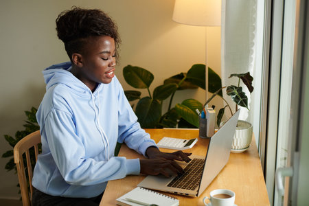 Young Black woman working on laptop at her desk in home office