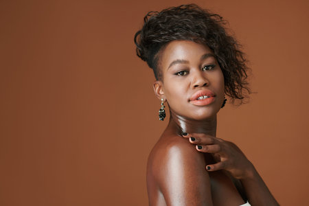 Portrait of happy young  woman with gemstone earring turning back and looking at cameraの写真素材