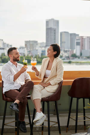 Best friends enjoying sweet cocktails when spending evening at rooftop bar with beautiful viewの写真素材