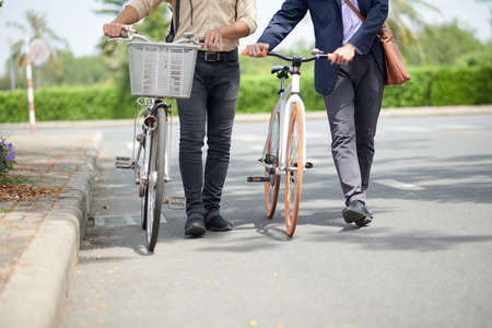 Cropped image of entrepreneurs with bicycles walking to office in morningの写真素材