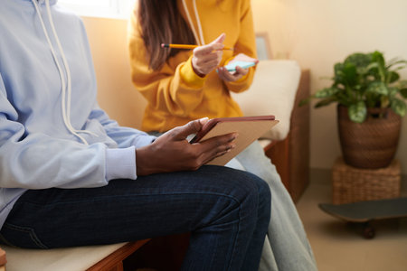 High school students copying important data from presentation on tablet computer on sticky notes to revise during dayの写真素材