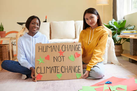 Smiling activists showing placard they made for climate change event in collegeの写真素材