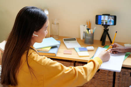 Schoolgirl wearing earbuds when attending online classの写真素材