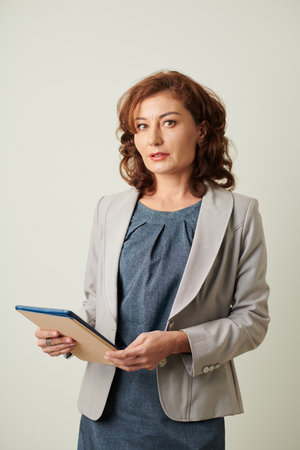 Portrait of business lady with tablet computer in hands looking at cameraの写真素材