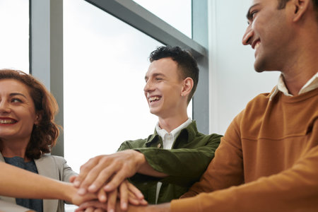 Excited young business, an stacking hands with his colleagues to experss trust and support