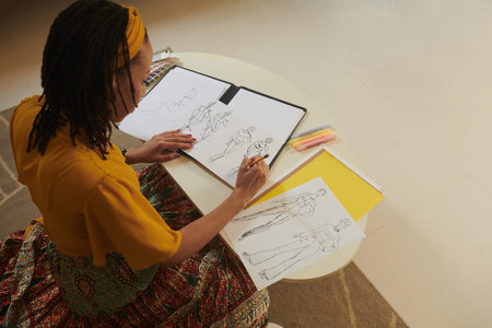 Fashion designer pondering over clothing items for her new collection and drawing sketches