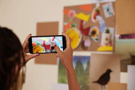 Female artist photographing floral collage she made for inspirationの写真素材
