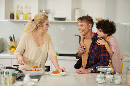 Happy woman adding bolognese sauce on top of portion of homemade pasta she cooked for family