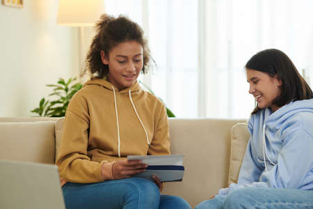 Smiling friends opening letter from college or university together to know if they are acceptedの写真素材