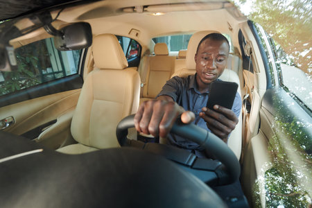 Distacted anxious man reading notifications on smartphone when driving carの写真素材