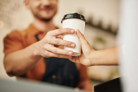 Closeup image of barista giving take-out coffee to customerの写真素材