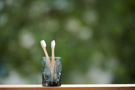 Glass with eco-friendly biodegradable bamboo toothbrush on window sillの写真素材