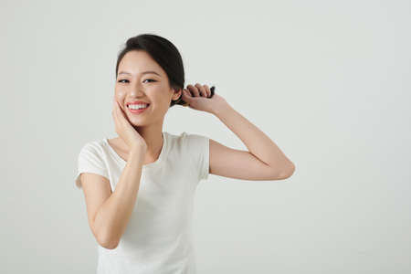 Portrait of young Asian woman twisting hair and touching her faceの写真素材