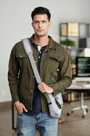 Portrait of serious young software developer ready to go home after working in office
