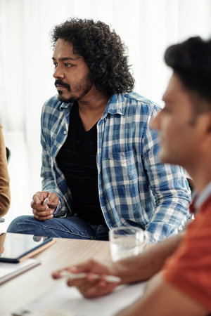 Pensive software developer listening to ideas of coworker at meeting