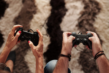 Hands of mature couple playing videogame at home on weekend