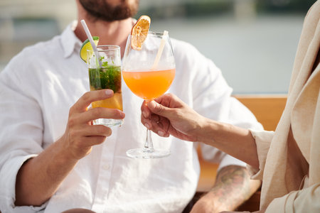 Cropped image of couple drinking fruit cocktails at outdoor partyの写真素材
