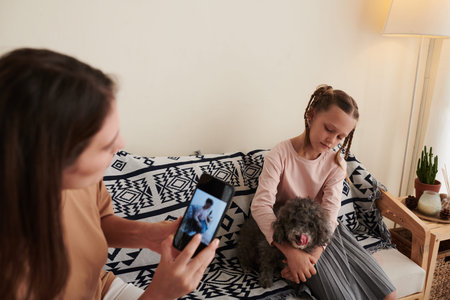 Young woman photographing daughter with little dog