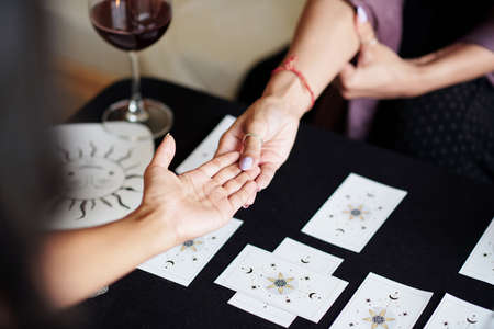Fortune teller asking young woman to give her hand for palm readingの写真素材