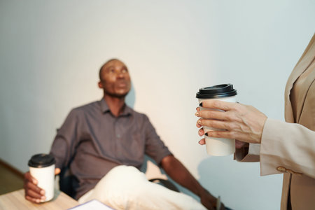 Business people drinking take out coffee when discussing work during breakの写真素材