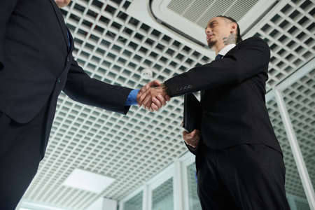 Business partners shaking hands , greeting each other, view from belowの写真素材