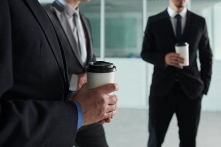 Cropped image of business people drinking take out coffee when spending break in office hallの写真素材