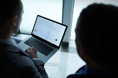 Civil engineer and investor discussing blueprint of new building at meetingの写真素材