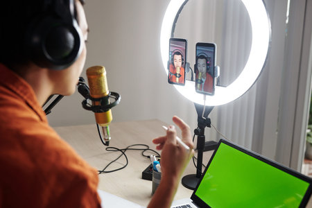 Young man using two smartphones and ring light when streaming online video on social media