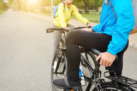 Cropped image of man wearing leggings and sports shorts when riding bicycle with friend in cityの写真素材