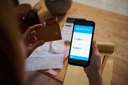 Hands of woman checking credit card loan via banking application on smartphoneの写真素材