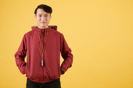 Portrait of positive coach with whistle on his neck smiling at camera
