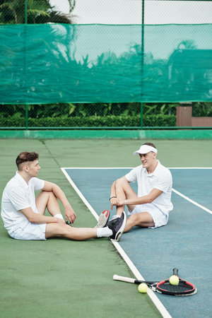 Positive players resting after game of tennis on outdoor courtの写真素材