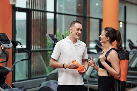 Smiling sportswoman talking to her trainer in gymの写真素材