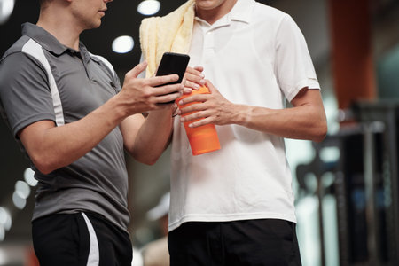 Cropped image of coach explaining client how to track progress in mobile application