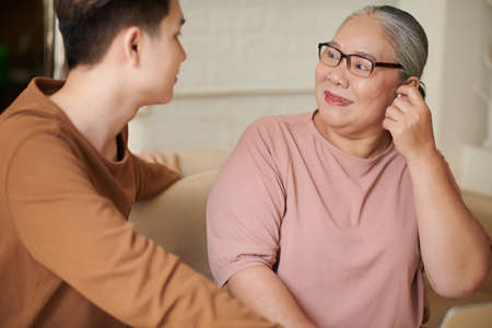 Happy aged woman putting in earbuds grandson presented her for birthdayの写真素材