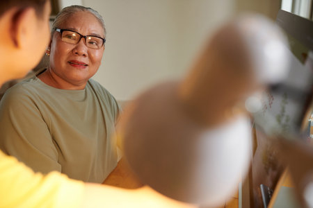 Senior woman listening to her grandson explaining how to work on computerの写真素材