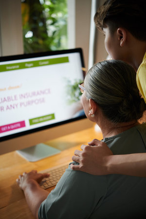 Teenage boy helping grandmother with ordering insurance policy online