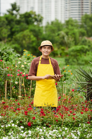Portrait of happy smiling outdoor flower shop owner standing with tablet computerの写真素材