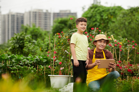 Happy faher brought his preteen son to flower nursery where he workerの写真素材