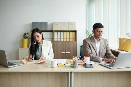 Serious business people concentrated on work sitting at desk in modern office