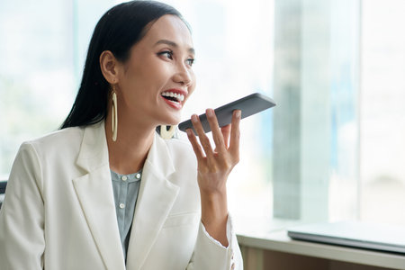 Portrait of joyful female entrepreneur recording voice message for business colleague