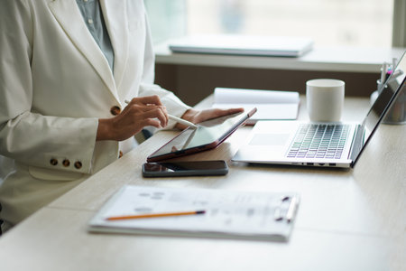 Close-up image of businesswoman checking documents and reports on tablet computerの写真素材