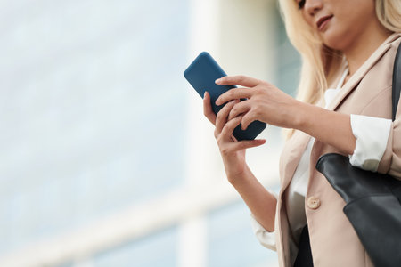 Cropped image of business lady texting her colleagues when waiting for taxi outdoorsの写真素材