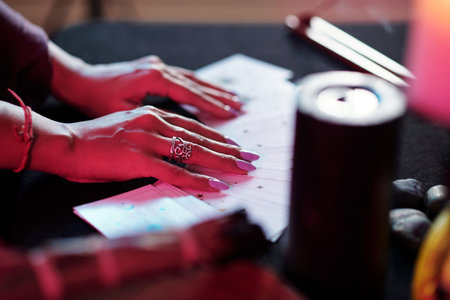 Manicured hands of fortune teller on spread tarot cards