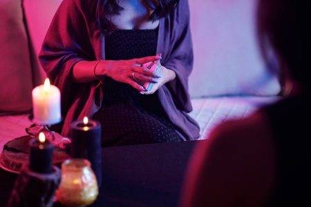 Cropped image of seer shuffeling tarot cards in front of clientの写真素材