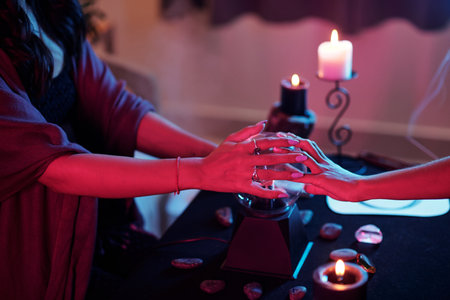 Hands of psychic and client putting hands of cystal ball to see futureの写真素材