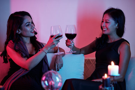 Smiling female friends drinking wine after telling fortune each otherの写真素材
