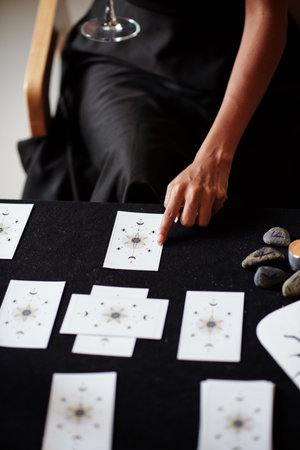 Woman spreading tarot cards on table and reading meaning for clientの写真素材