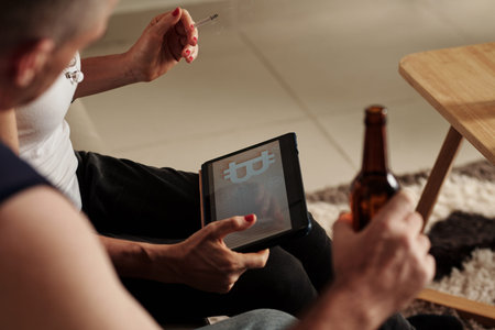 Mature couple smoking and drinking beer when reading article on bitcoin price prediction